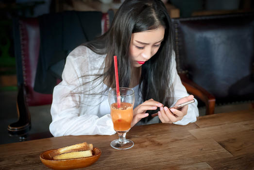 咖啡厅玩手机的年轻女生图片素材免费下载