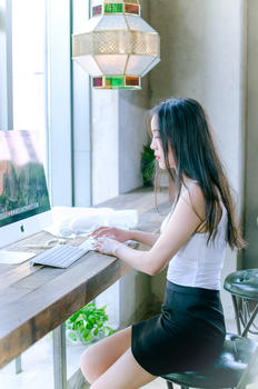 窗边玩电脑的年轻女性图片素材免费下载