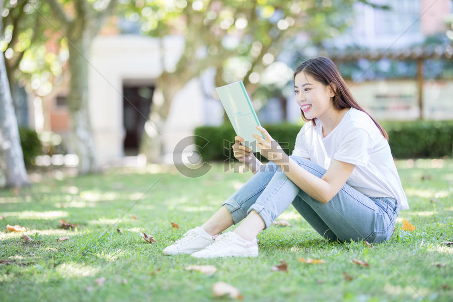 坐在校园草坪上看书的女学生图片素材免费下载