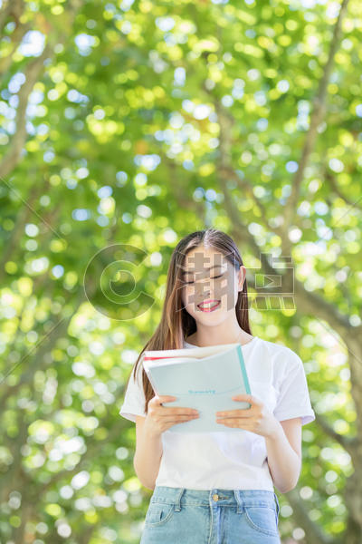 校园林荫道上微笑看书的学生图片素材免费下载
