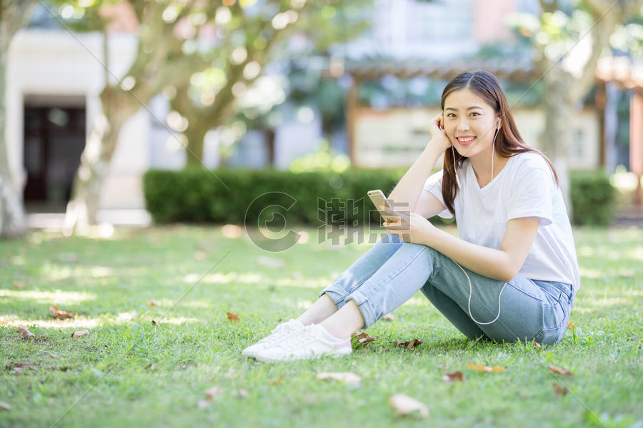 坐在校园草坪上玩手机的女生图片素材免费下载