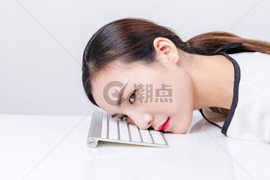 职业女性靠在键盘上棚拍图片素材免费下载
