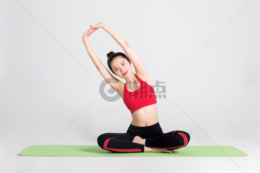 坐在瑜伽垫上做伸展运动的女性图片素材免费下载