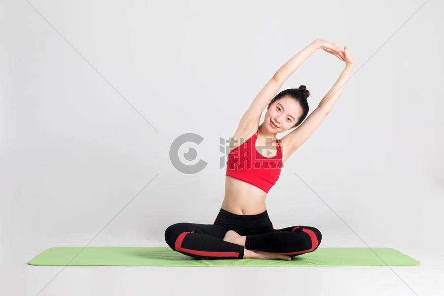 坐在瑜伽垫上做伸展运动的女性图片素材免费下载