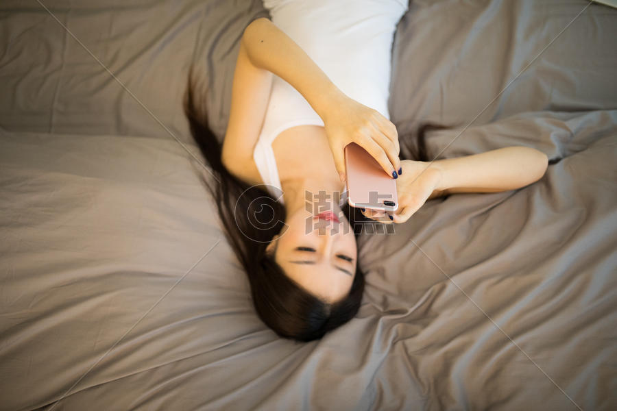 躺在床上玩手机的美女图片素材免费下载