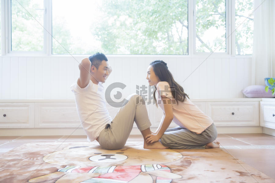 年轻夫妇在客厅做仰卧起坐图片素材免费下载