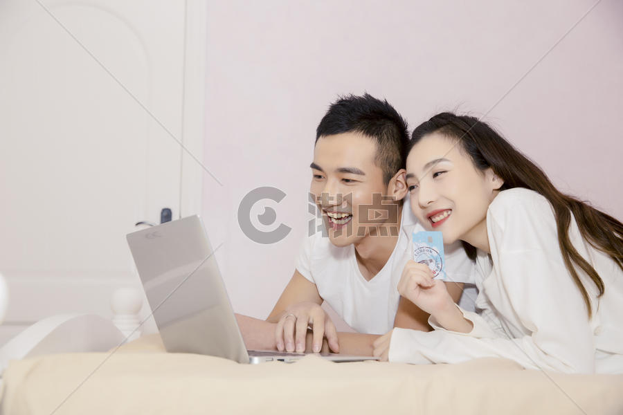年轻夫妇在卧室用电脑购物图片素材免费下载