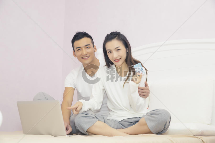 年轻夫妇在卧室用电脑购物图片素材免费下载