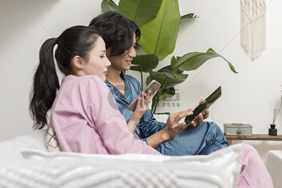 情侣在客厅休息玩手机平板电脑图片素材免费下载