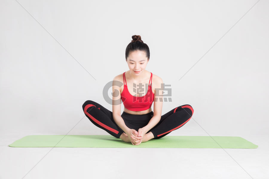 瑜伽垫上做瑜伽动作的年轻女性图片素材免费下载