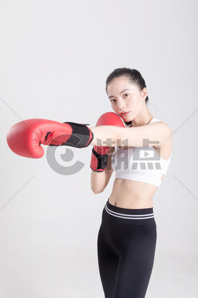 戴着拳击手套打拳出拳的年轻运动女性图片素材免费下载
