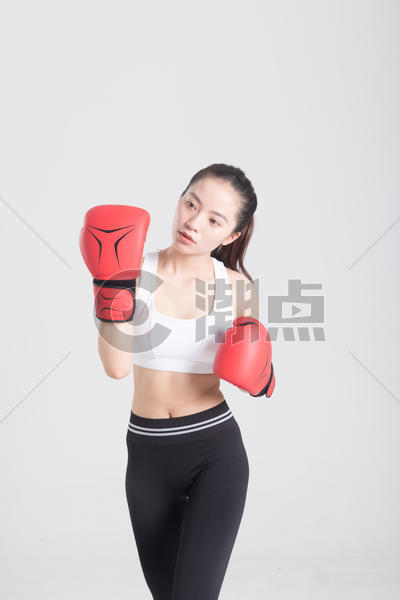 戴着拳击手套打拳出拳的年轻运动女性图片素材免费下载