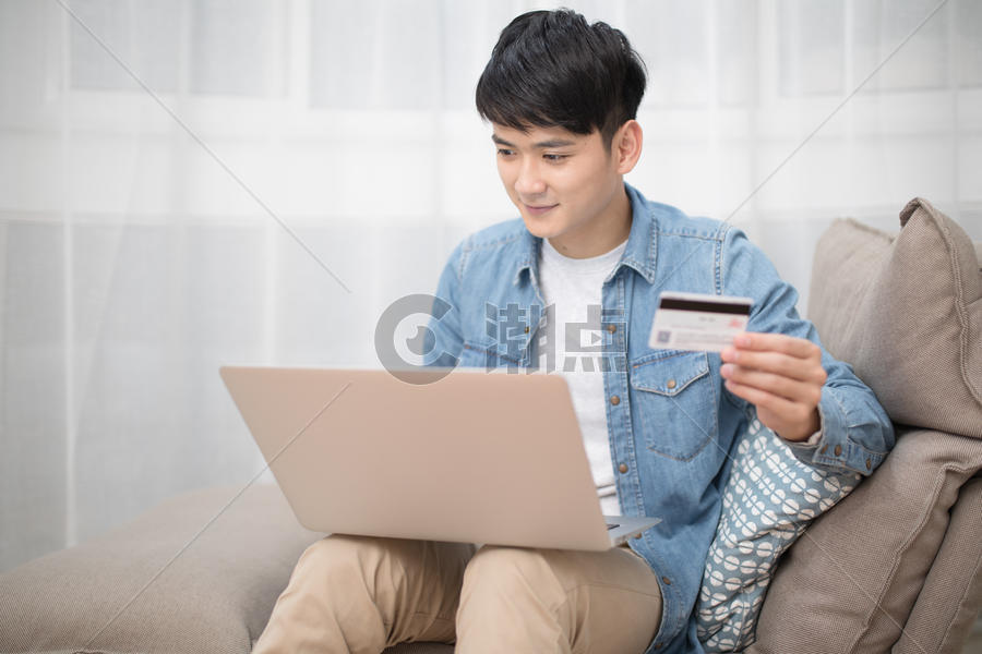 拿着银行卡使用电脑网购的男性图片素材免费下载