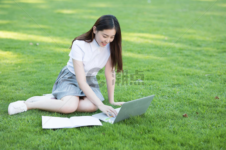 坐在草坪上使用笔记本电脑的同学图片素材免费下载