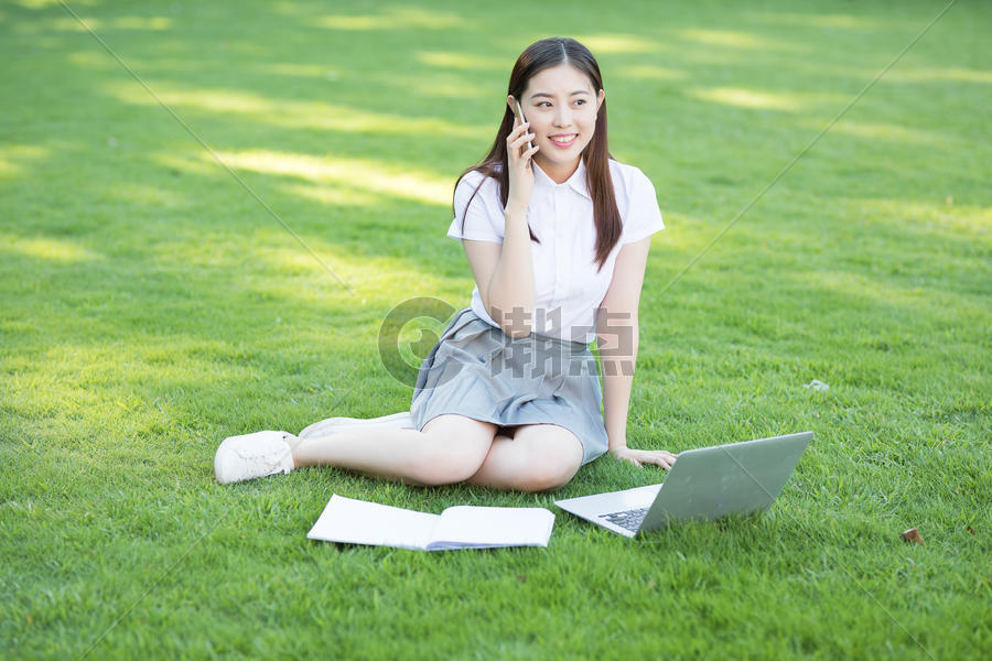 坐在草坪上的打电话的女生图片素材免费下载