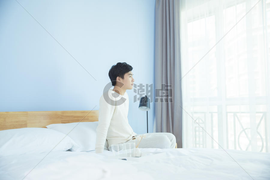 卧室里坐在床边的年轻男性图片素材免费下载