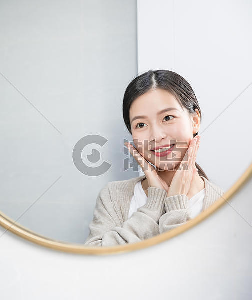 在家照镜子护肤美容的年轻女性图片素材免费下载