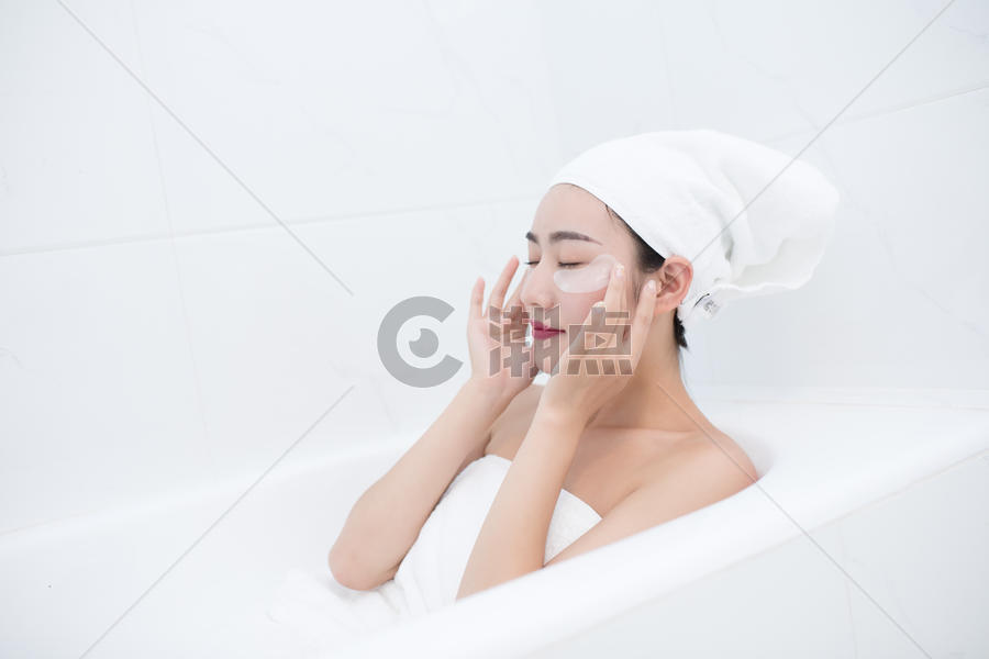 包着头发坐在浴缸里敷眼膜的年轻美女图片素材免费下载