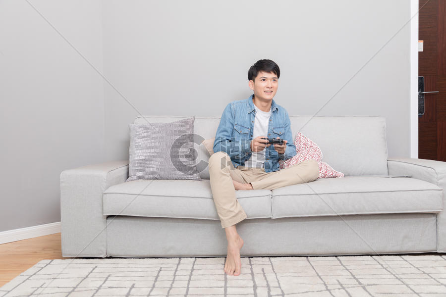坐在沙发上玩游戏的男子图片素材免费下载