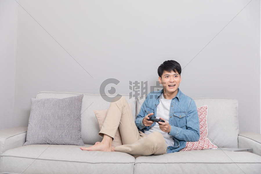 坐在沙发上玩游戏的男子图片素材免费下载