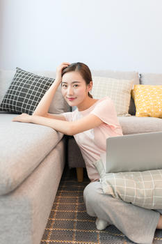 年轻美女靠着沙发玩电脑图片素材免费下载