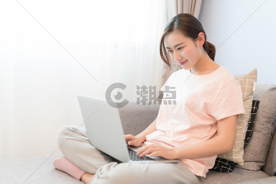 坐在沙发上玩电脑的年轻女性图片素材免费下载