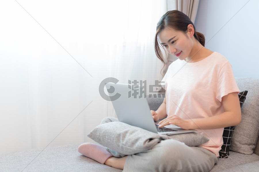 坐在沙发上玩电脑的年轻女性图片素材免费下载