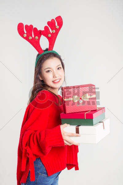 手拿礼物盒的圣诞装扮女性棚拍图片素材免费下载