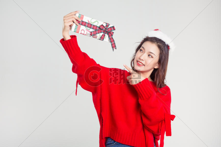 手拿礼物盒的圣诞装扮女性棚拍图片素材免费下载