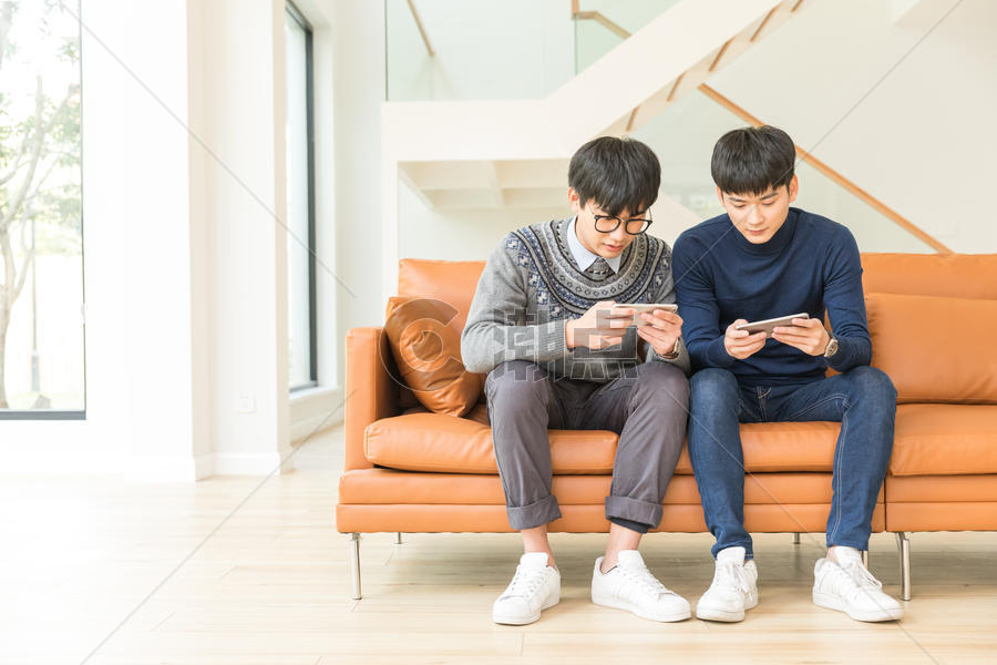 坐在客厅里玩手机的年轻人图片素材免费下载
