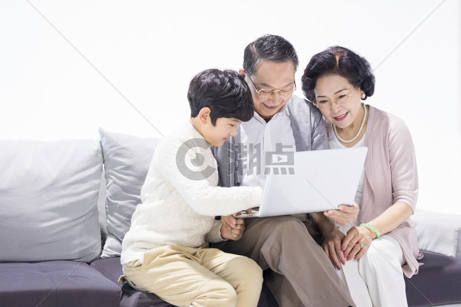 爷爷奶奶和孙子开心地坐在沙发上使用电脑图片素材免费下载