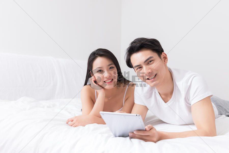 年轻夫妻床上开心看平板图片素材免费下载