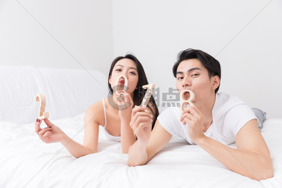 年轻夫妻开心躺床上手拿2018图片素材免费下载