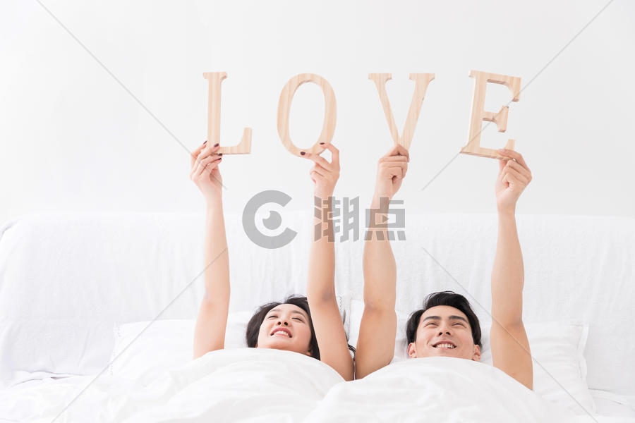 年轻夫妻躺床上手拿LOVE图片素材免费下载