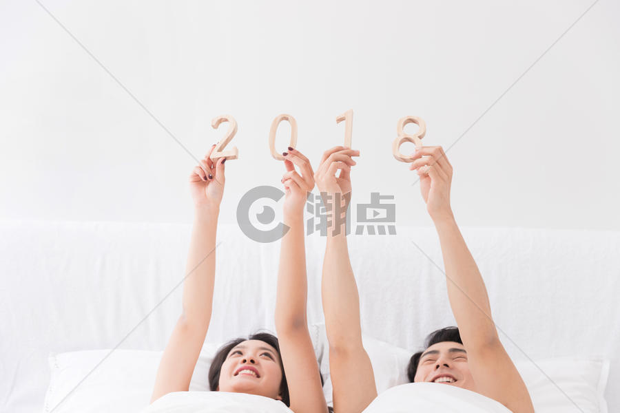 年轻夫妻躺床上手拿2018图片素材免费下载