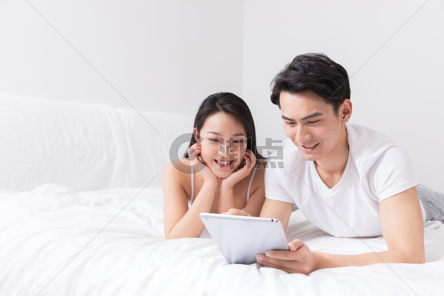年轻夫妻床上开心看平板图片素材免费下载