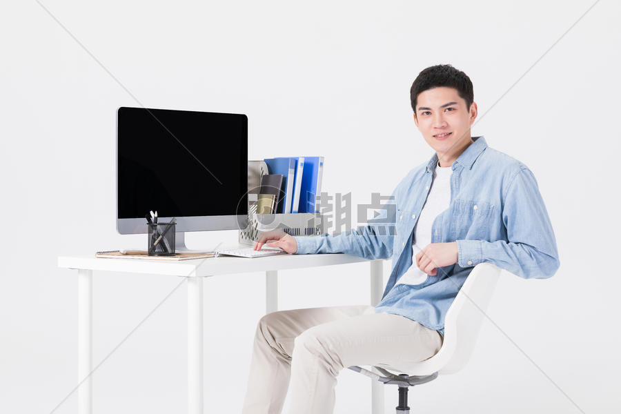 年轻男性坐在办公桌前工作图片素材免费下载