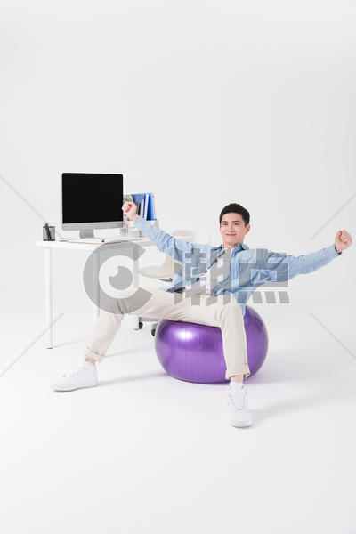 年轻职员坐在瑜伽球上锻炼图片素材免费下载