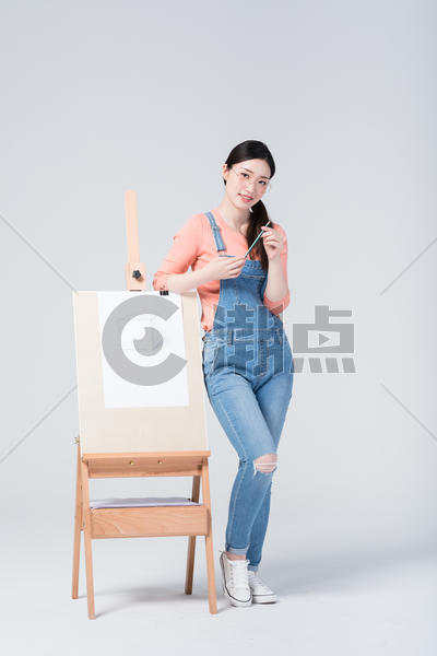 青年美女手拿铅笔站在画架旁图片素材免费下载