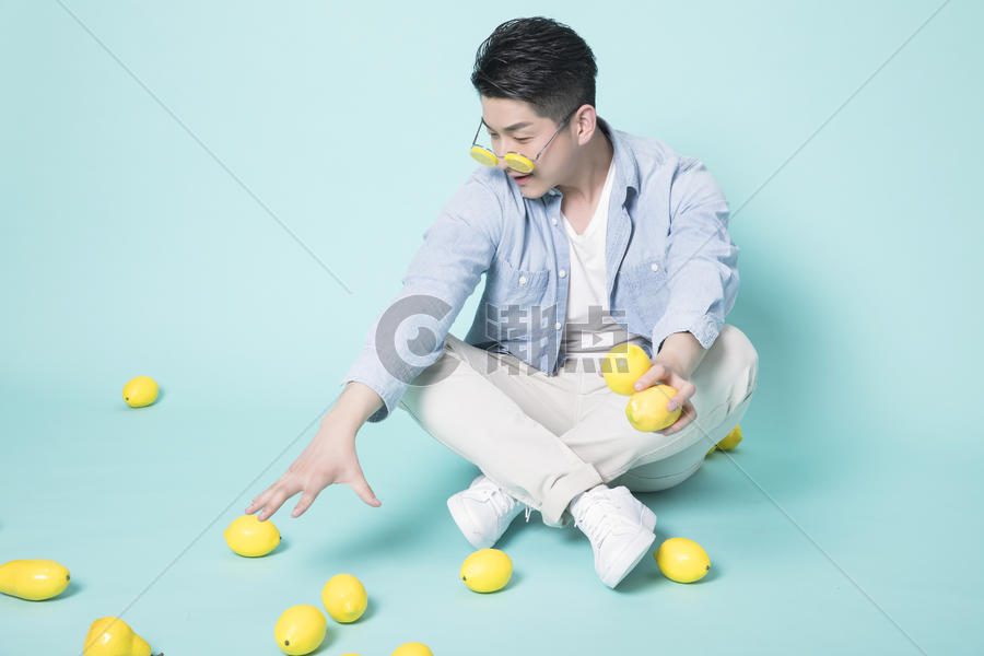 坐在地上拿着柠檬的青年男性图片素材免费下载