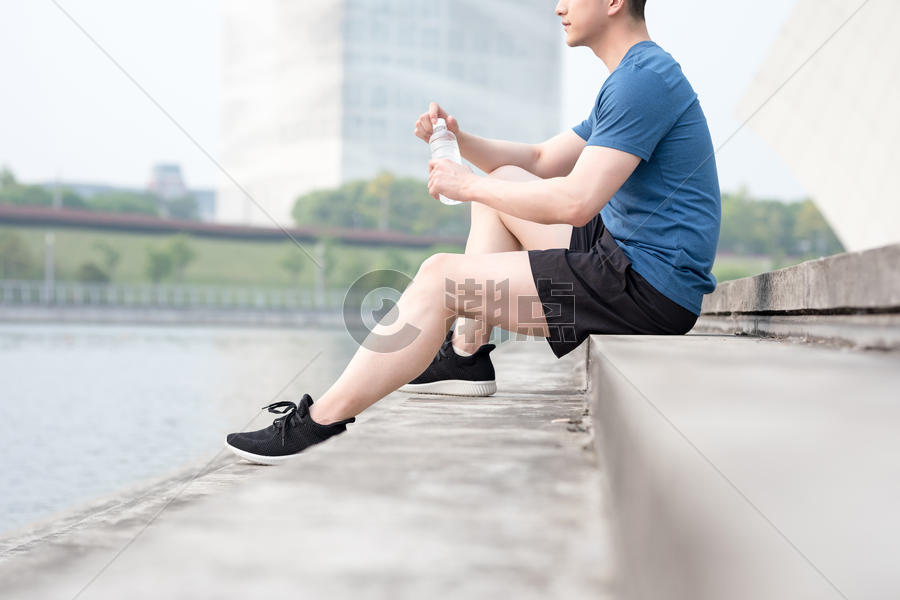 运动后坐着休息喝水放松的年轻男性图片素材免费下载