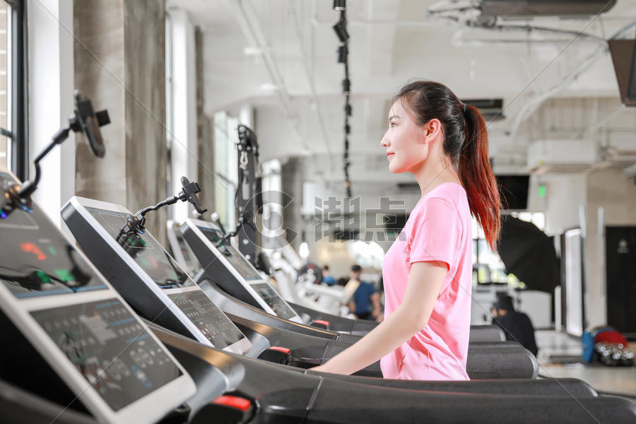 年轻女性健身房使用跑步机跑步图片素材免费下载