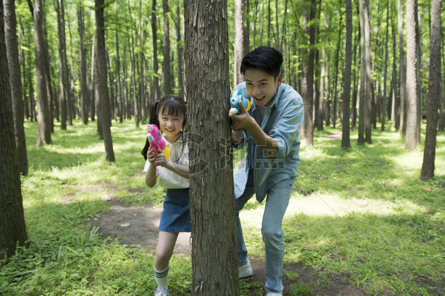 爸爸与孩子在树林中玩水枪图片素材免费下载