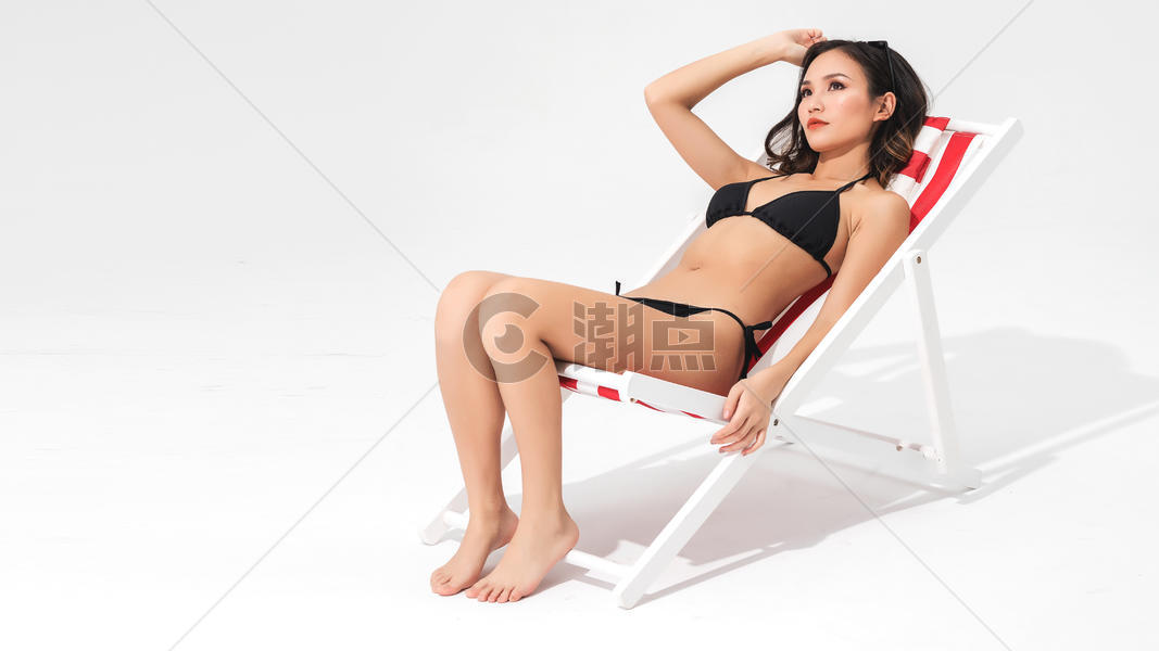 黑色比基尼泳装美女坐在沙滩躺椅上图片素材免费下载