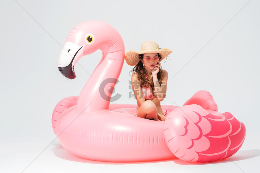穿粉色比基尼的可爱卖女坐在火烈鸟游泳圈图片素材免费下载