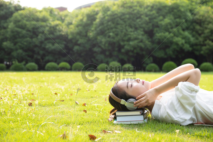 青春学生躺草地上听音乐图片素材免费下载
