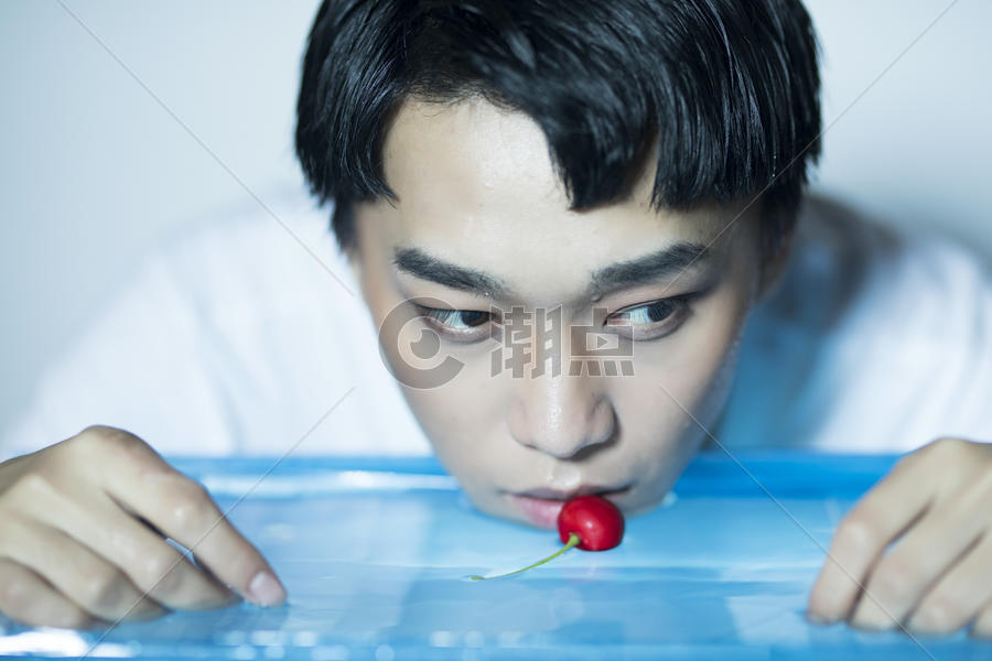 拿着樱桃在水面放空的青年男性图片素材免费下载