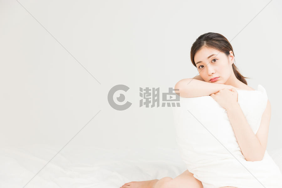 年轻女性床上抱着枕头放松图片素材免费下载