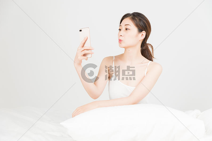 年轻女性床上手机自拍图片素材免费下载