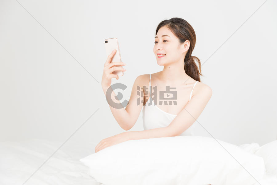 年轻女性床上手机自拍图片素材免费下载